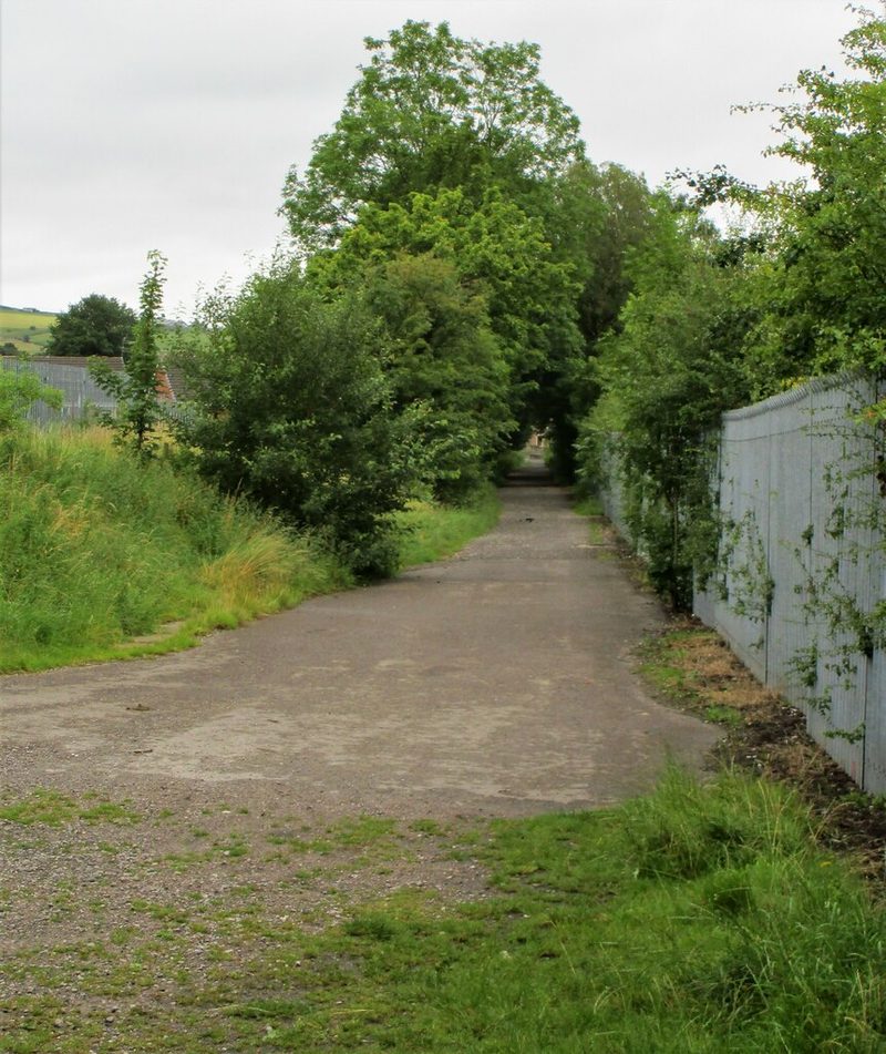 A surfaced path between trees and a metal fence along the line of the former colliery tramway in Milnrow.