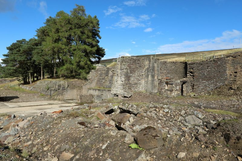 Stone walls and levelled ground of the old lead ore works at Carrshield lying in rough pasture beside the West Allen, with open fell rising behind