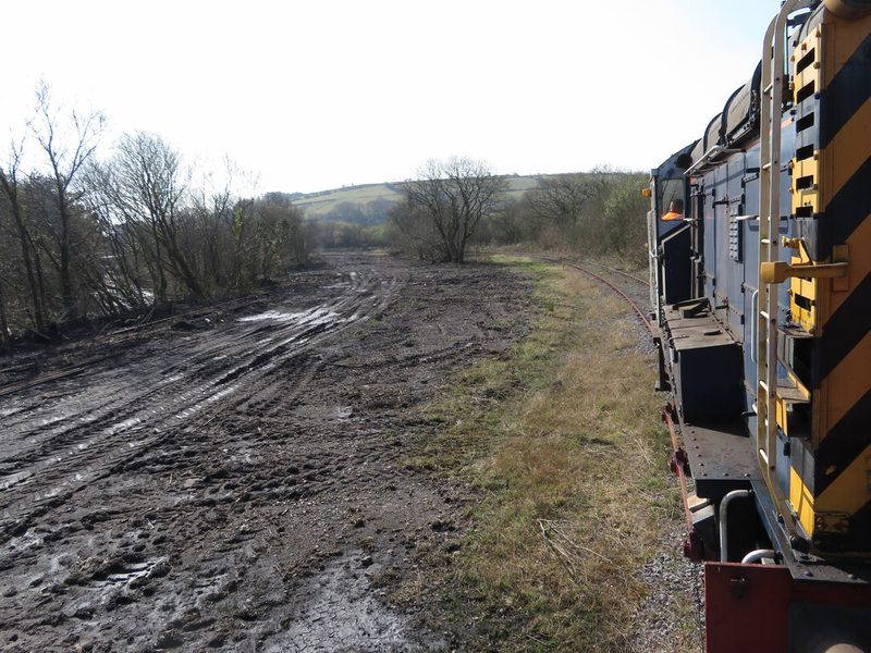 A small diesel shunter and brake van on a heritage railway line beside the grassed former Cynheidre colliery site.