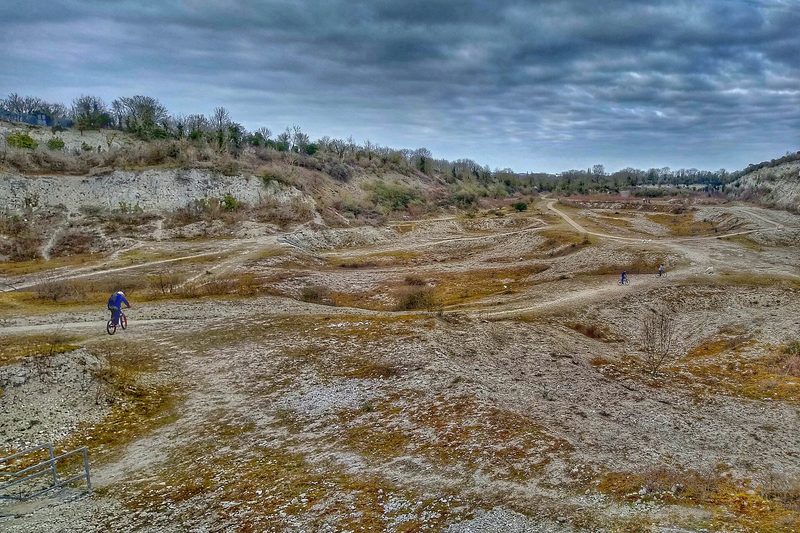 Cyclists on the surfaced path below the chalk faces of Cherry Hinton east pit in March 2021.