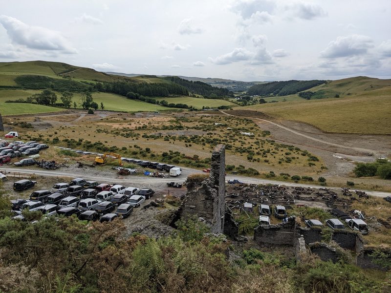 Vehicles ranked across the former Frongoch mine ground in July 2022, the site then in use as a Range Rover breaker's yard.
