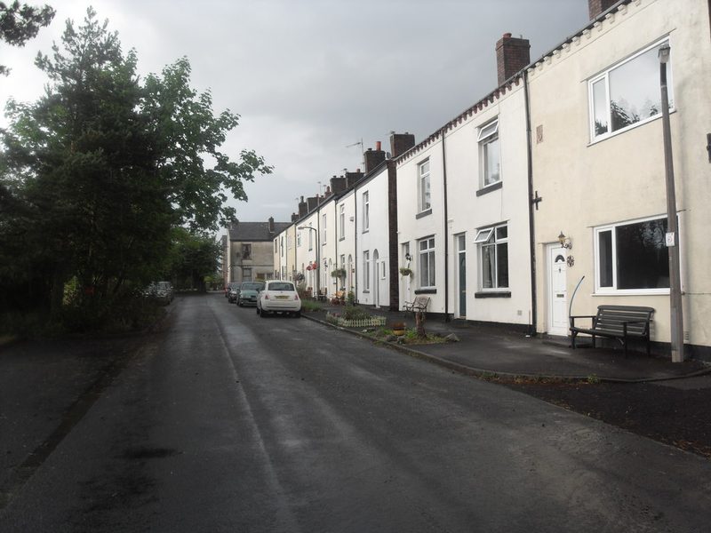A terrace of painted two-storey miners' cottages along a quiet village street