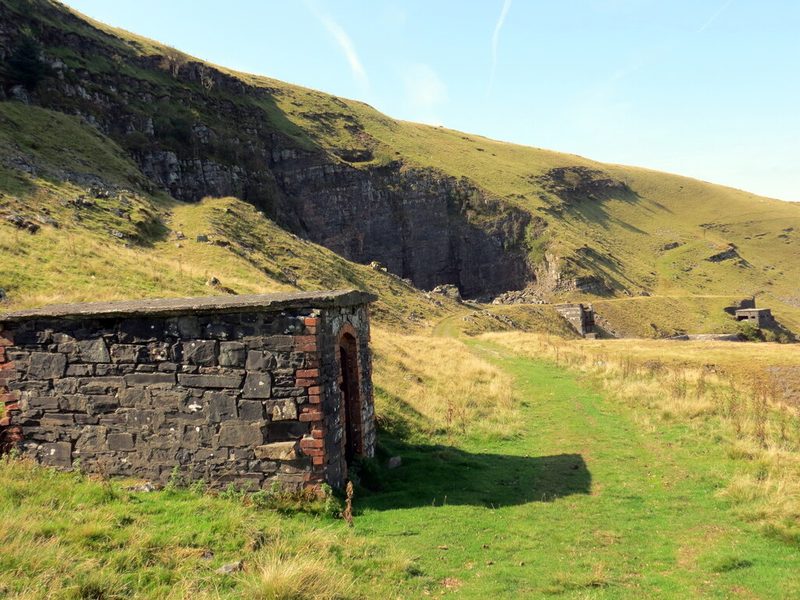 The disused Heol Senni quarry cut into the hillside above the Senni valley, its bare brownstone faces standing above scree and rough grass