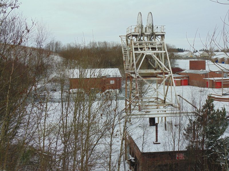 The surviving steel headframe and brick engine house of Highhouse Colliery among industrial estate buildings in snow, 2016.