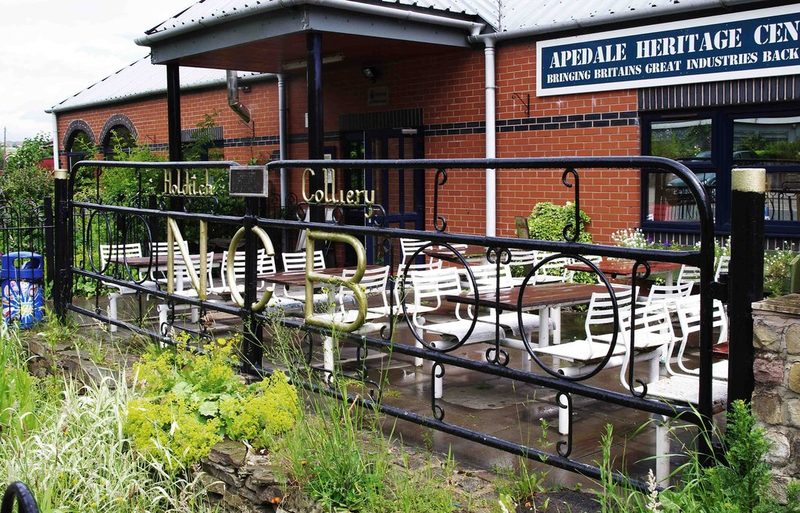 Painted steel colliery gates bearing the National Coal Board name, re-erected at a heritage centre entrance.
