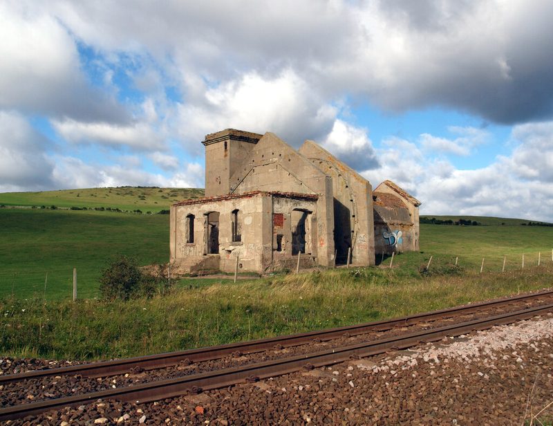 The roofless stone shell of the Guibal fan house standing on the cliff top above Saltburn, with the railway running in front of it