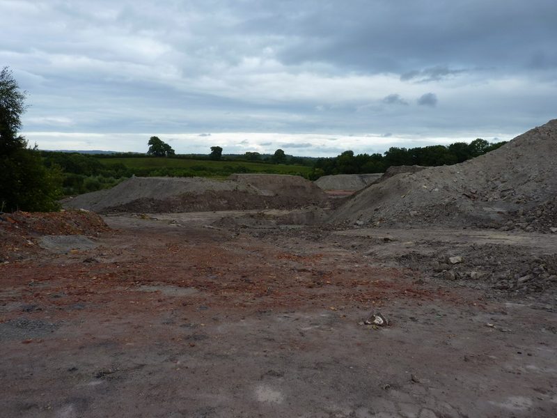 A stepped opencast clay working cut into a field at Broseley, the pale worked faces exposed above a pool of standing water.