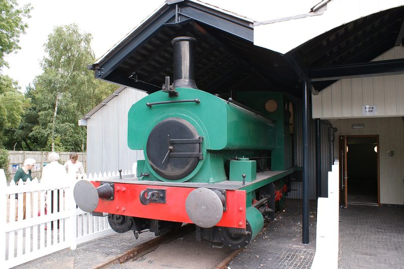 A small preserved 0-4-0 saddle tank locomotive standing on display track at a museum.