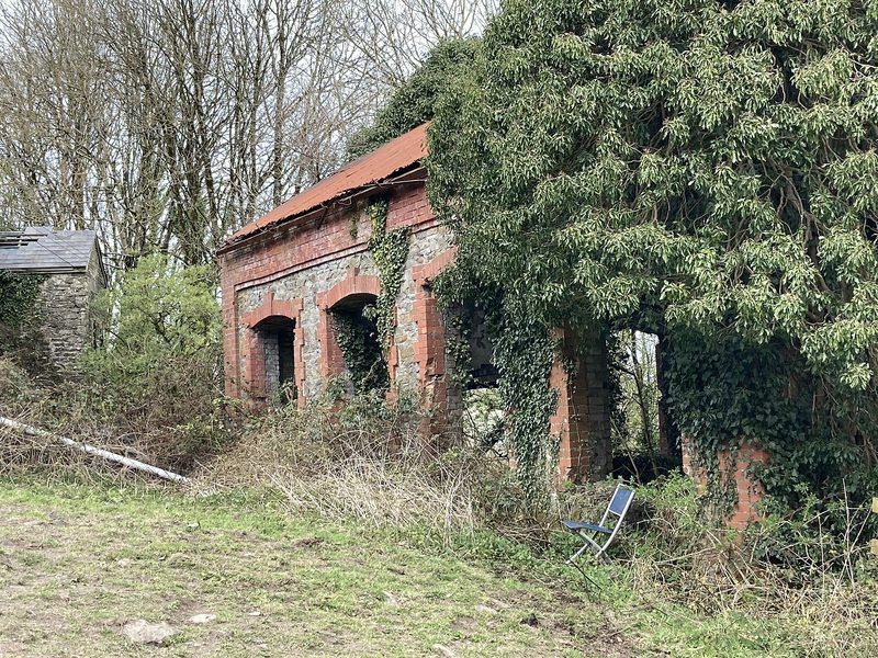 A tall brick winding engine house with arched openings, now used as a farm hay barn.