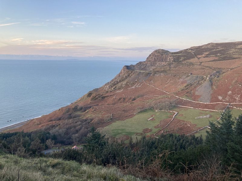 The abandoned granite workings on the steep hillside above Nant Gwrtheyrn on the Llŷn peninsula, with quarry terraces cut into the slope above the sea