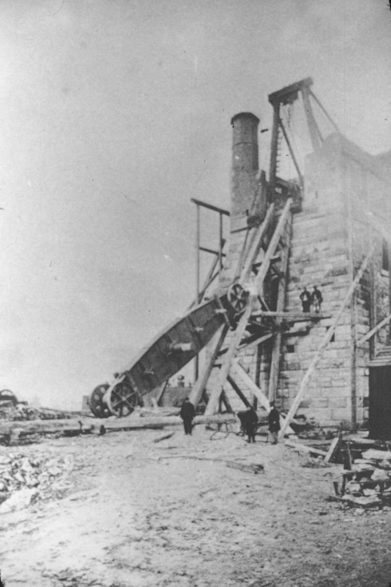 A nineteenth-century photograph of the colliery surface, with miners standing among the pithead buildings and headgear.