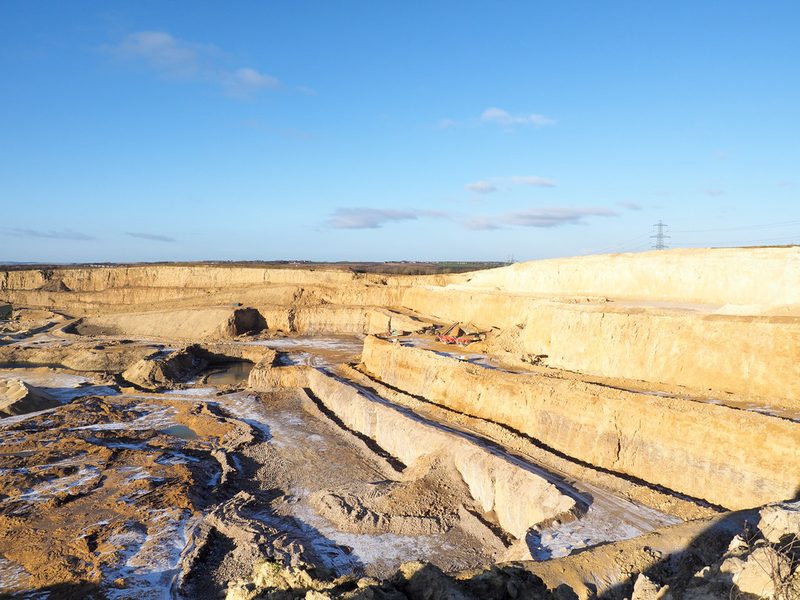 A working limestone face at Raisby cut in tiers, pale rock stepping down to the quarry floor