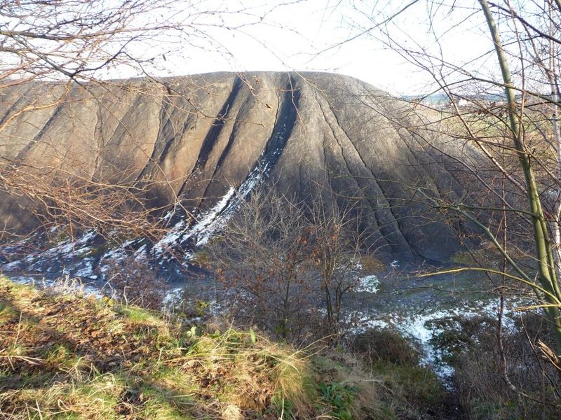 A grassed-over spoil mound rising above rough ground at Robin Hood, the last shape the colliery left on the landscape