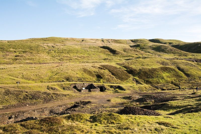 The roofless stone walls of a small building in a bare upland valley near the mine level.