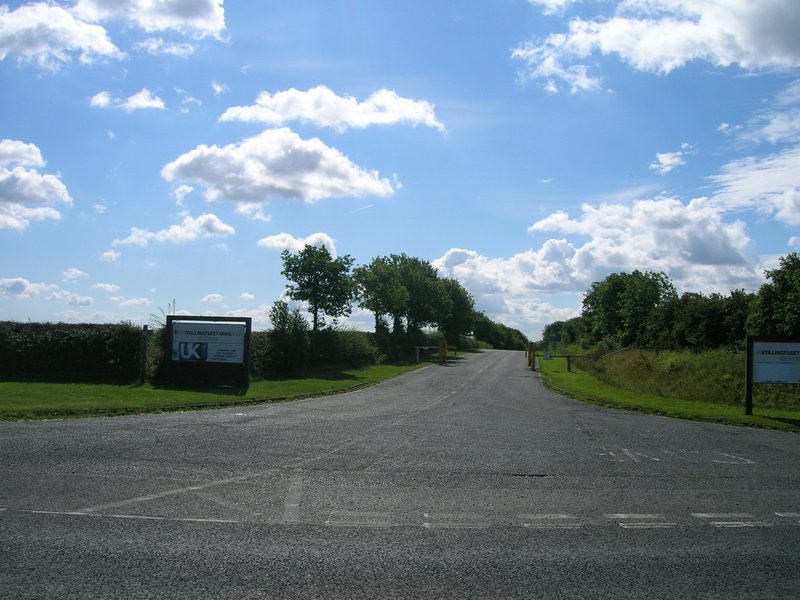 The tarmac entrance road to Stillingfleet Mine between hedges and trees, with UK Coal signboards at each side, in 2011