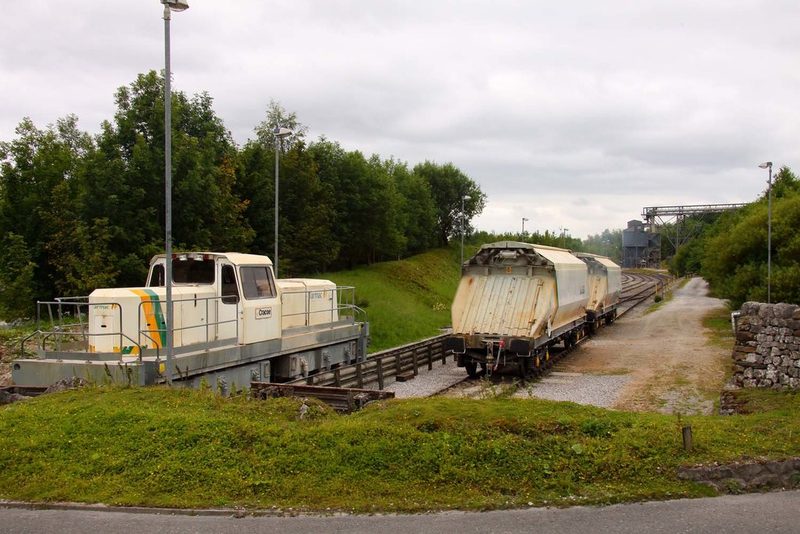 A cream Tarmac-liveried shunting locomotive named Cracoe beside covered hopper wagons in the quarry sidings