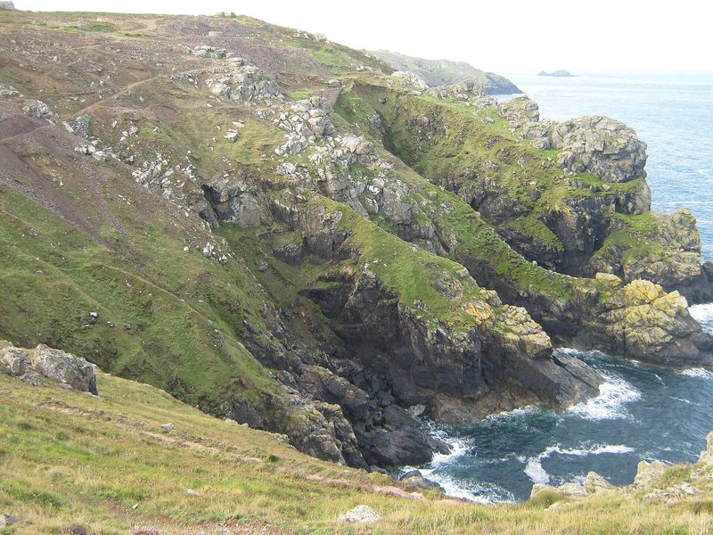 Walled shafts and spoil of Wheal Cock on the cliff top seen along the coast path from the Levant direction.