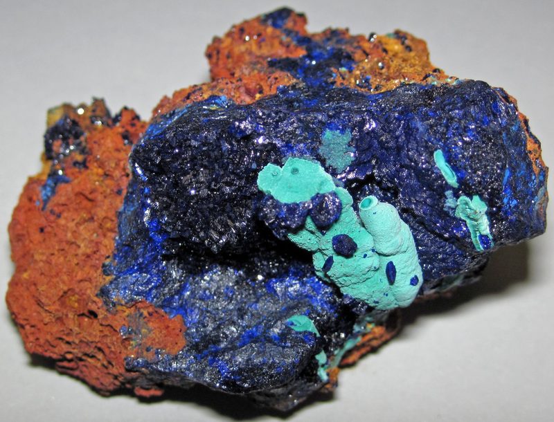Azurite and malachite on iron-oxide gossan — the weathered, oxidised "iron cap" that often marks a mineral vein at surface.