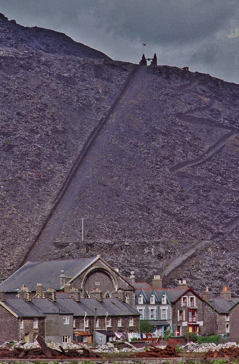 The disused main incline from Oakeley Quarry running straight down the vast grey slate spoil tip directly above the terraced houses of Blaenau Ffestiniog.