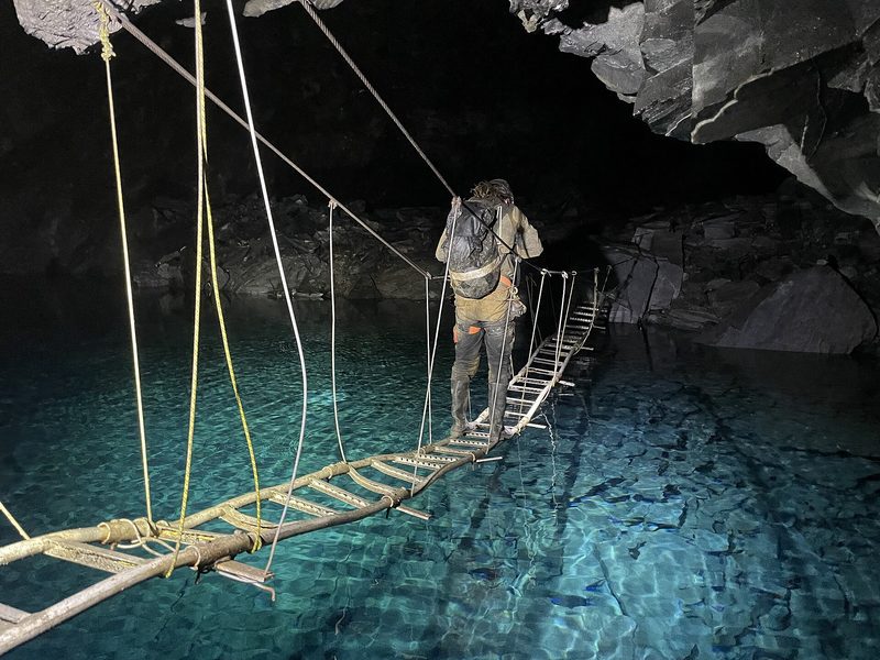A vast dark underground slate chamber with steeply pitched rock walls rising out of sight.