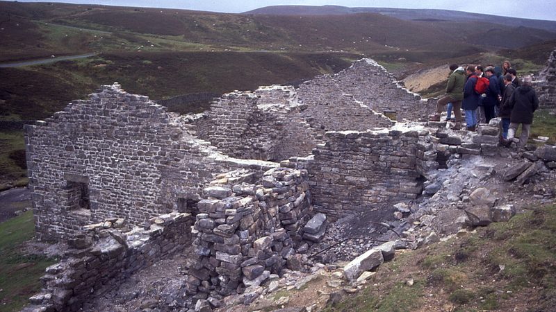 The ruined stone buildings of Surrender lead smelt mill in a Swaledale valley bottom.